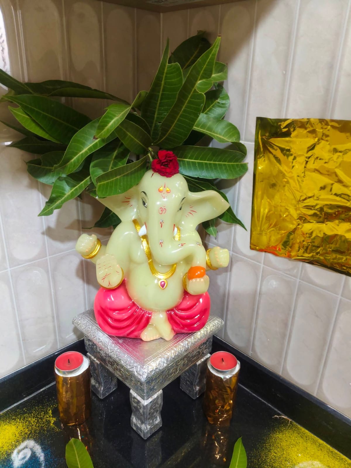 A Ganesh murti with mango leaves, set for a home puja